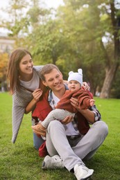 Happy parents with their adorable baby on green grass in park