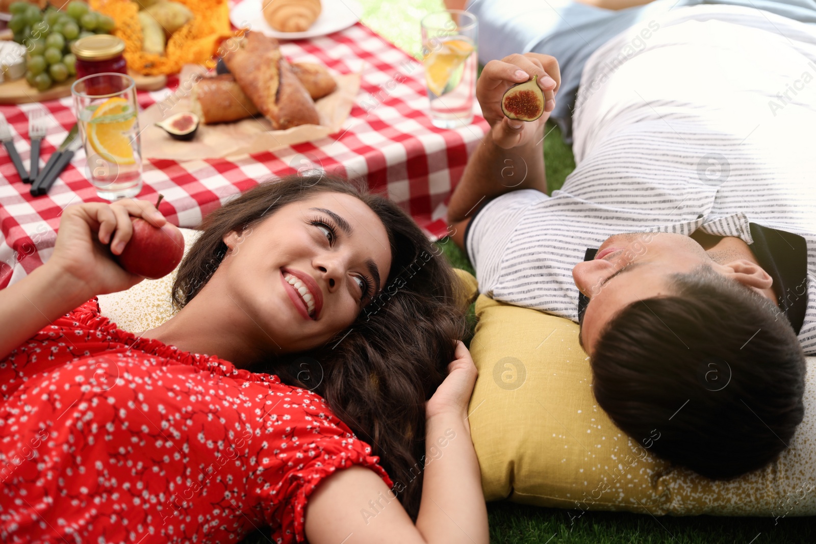 Photo of Happy couple with tasty snacks imitating picnic at home