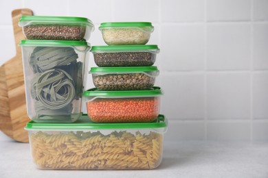 Plastic containers filled with food products on white table near tiled wall. Space for text