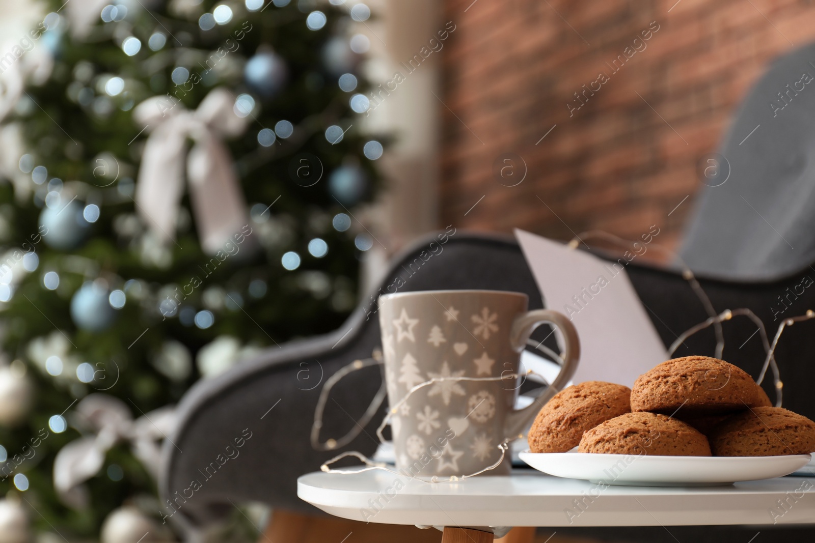 Photo of Book with treat on table and Christmas tree in stylish living room interior