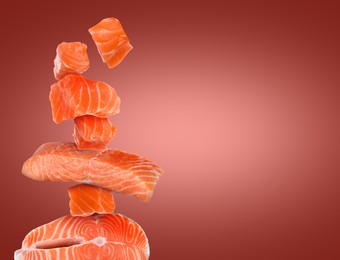 Image of Cut fresh salmon falling on dark red gradient background, space for text