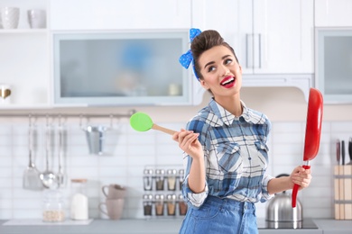 Funny young housewife with frying pan in kitchen