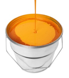 Photo of Pouring orange paint into bucket on white background