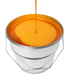 Pouring orange paint into bucket on white background