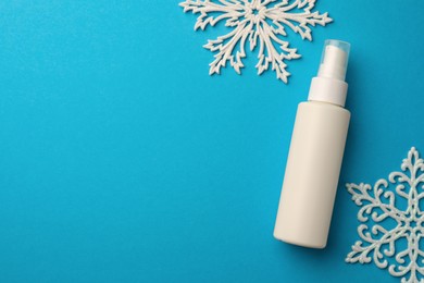 Hand cream and snowflakes on light blue background, flat lay with space for text. Winter skin care