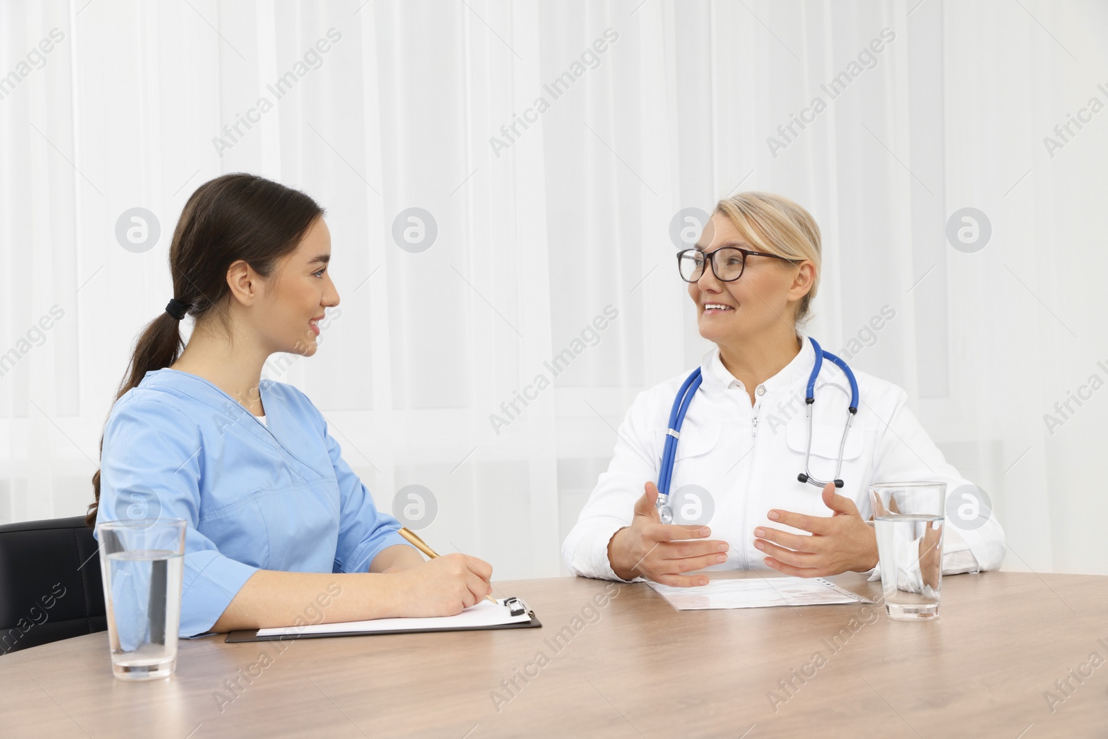 Photo of Medical conference. Doctors having discussion at wooden table in office