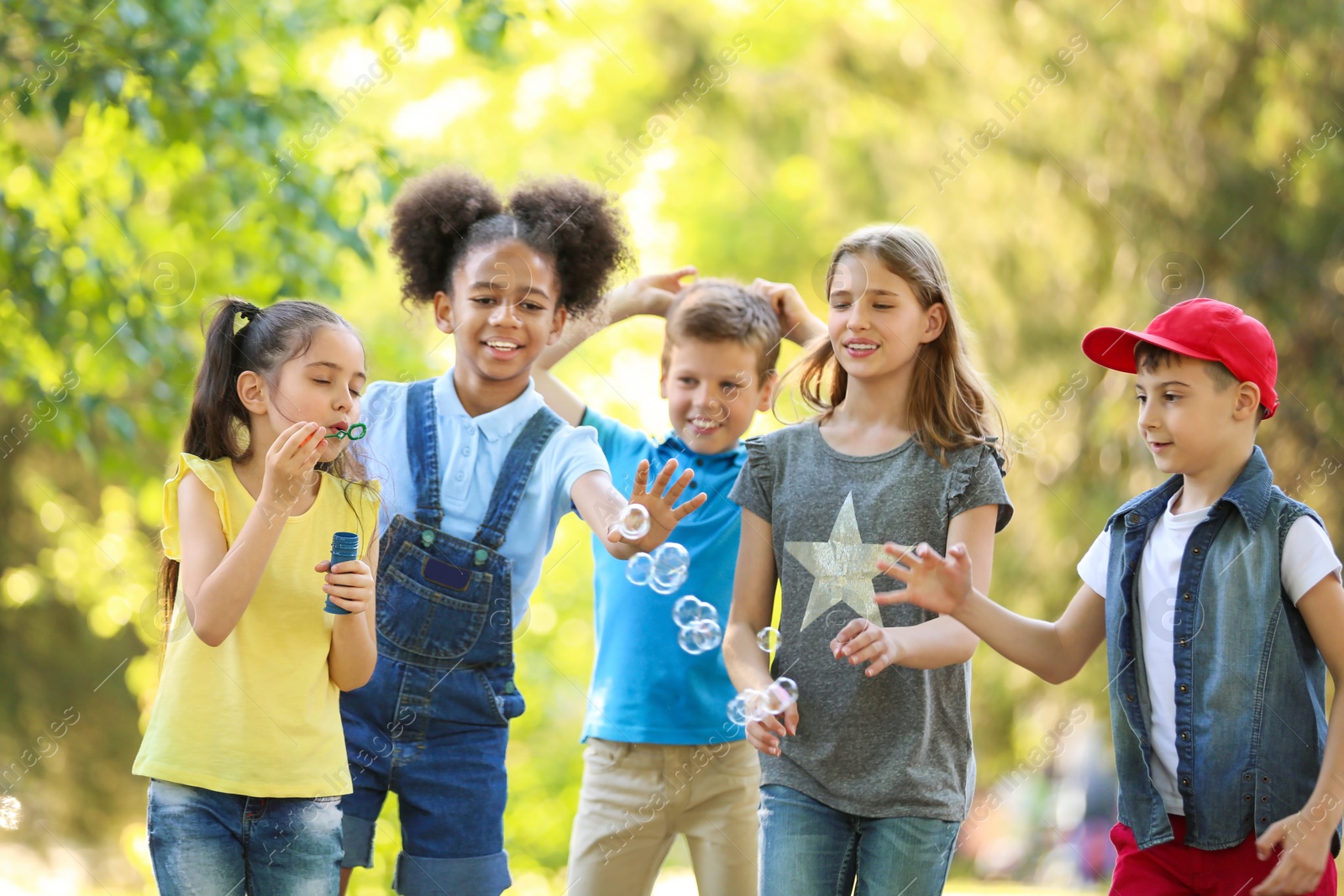 Photo of Cute little children playing with soap bubbles outdoors on sunny day