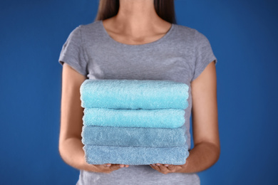 Woman holding fresh towels on blue background, closeup