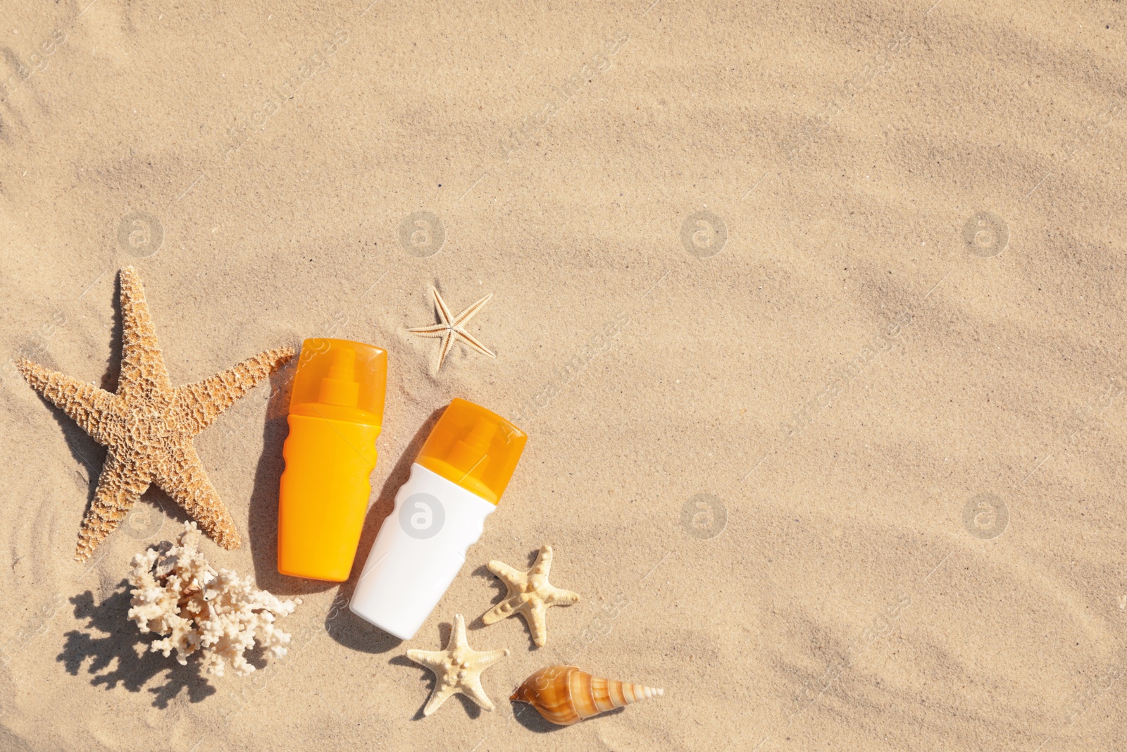 Photo of Flat lay composition with bottles of sunblock on sandy beach. Space for text