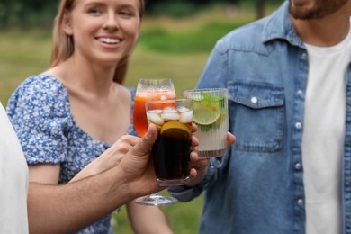 Photo of Friends clinking glasses with cocktails outdoors, selective focus