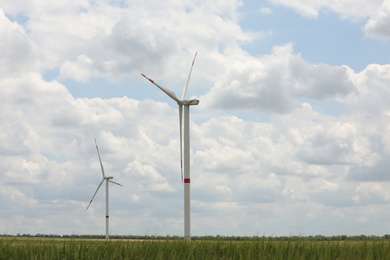 Modern wind turbines in field on cloudy day. Alternative energy source