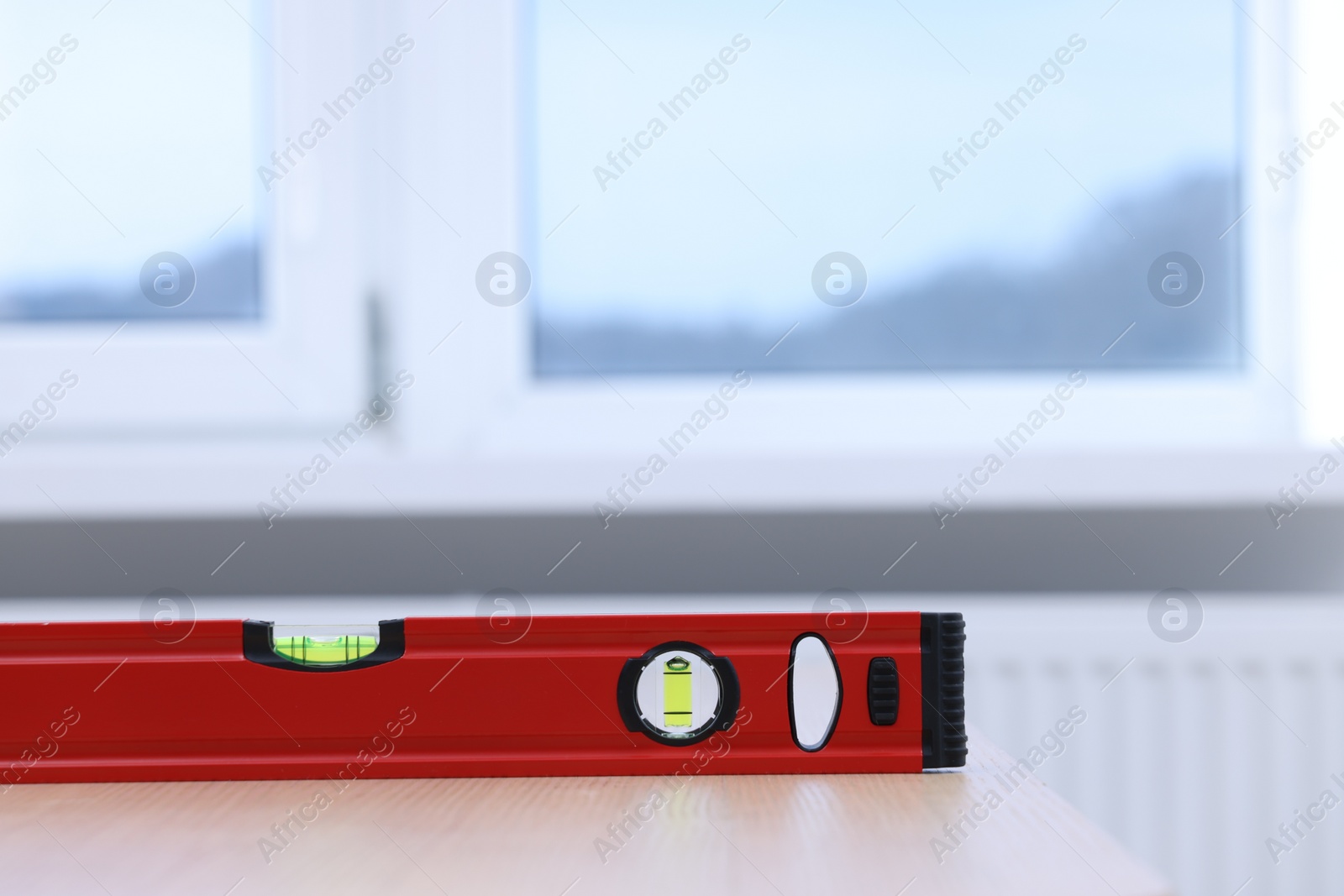 Photo of Red building level on wooden table indoors, closeup. Space for text