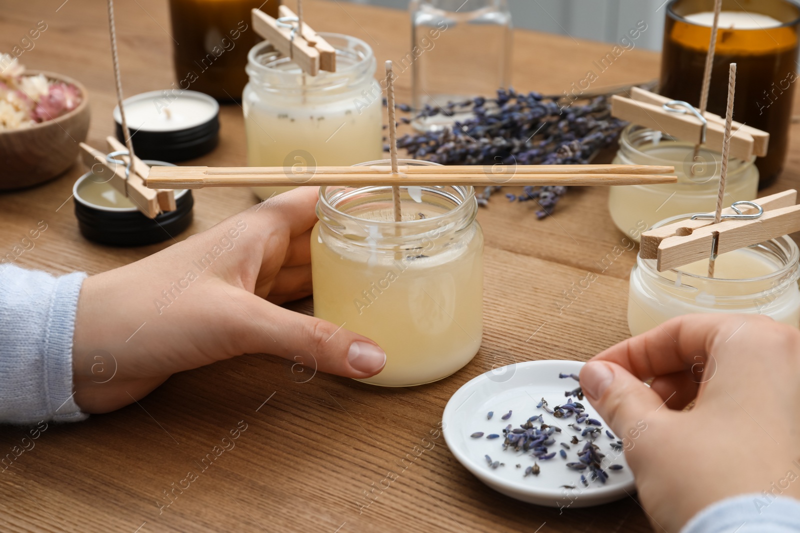 Photo of Woman making aromatic candles at wooden table, closeup