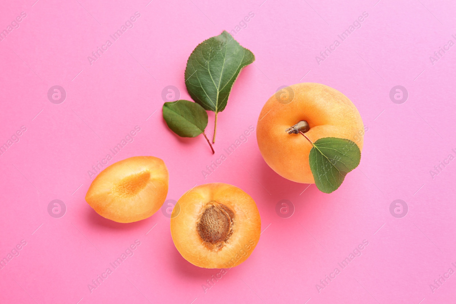 Photo of Delicious ripe sweet apricots on pink background, flat lay