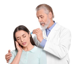 Doctor dripping medication into woman's ear on white background