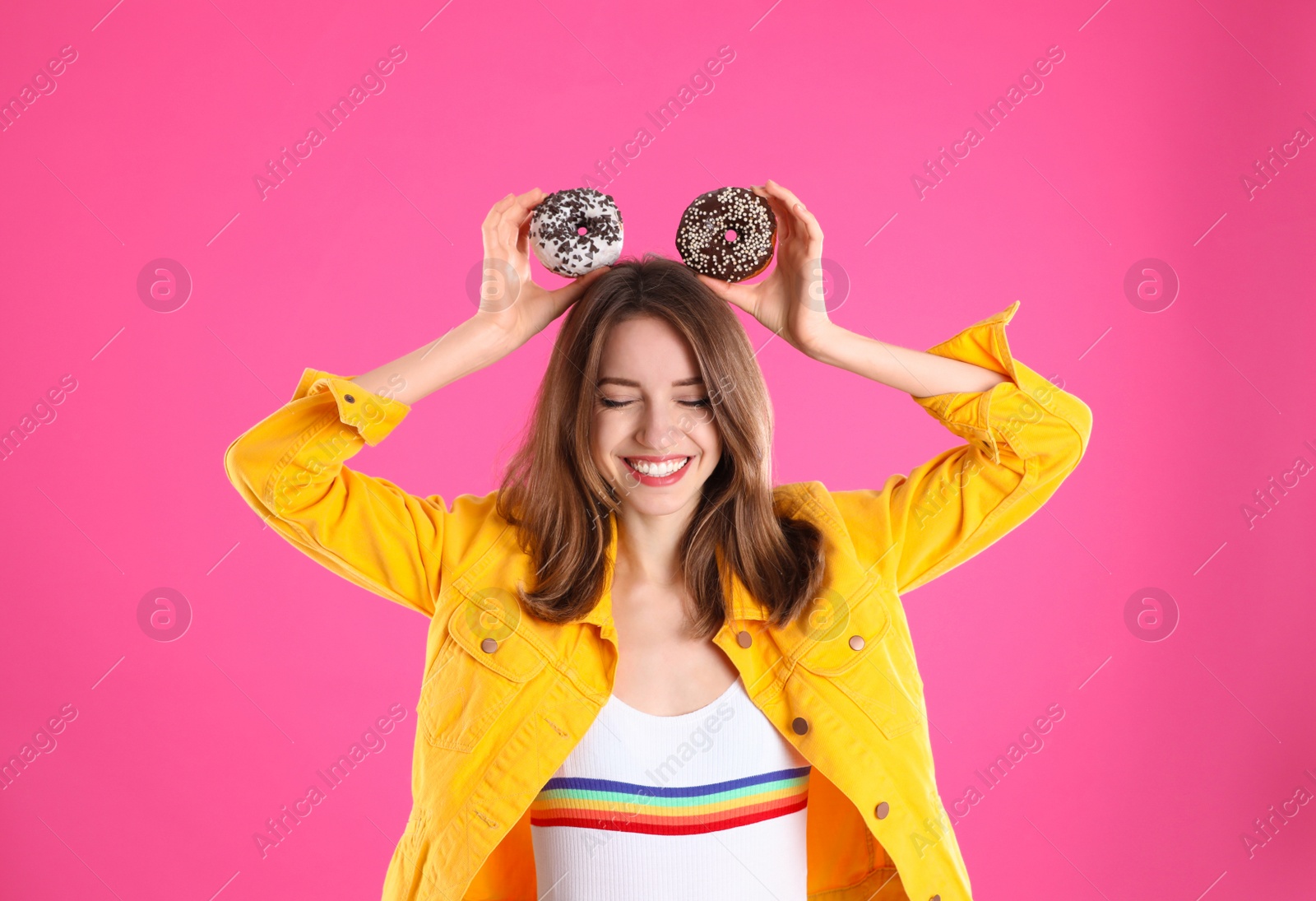 Photo of Beautiful young woman with donuts on pink background