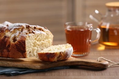 Photo of Delicious yeast dough cake and tea on wooden table, closeup