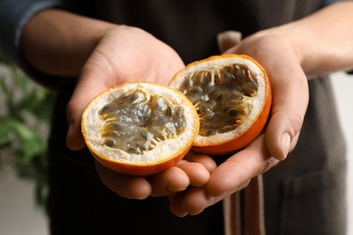 Woman with halves of granadilla, closeup. Exotic fruit