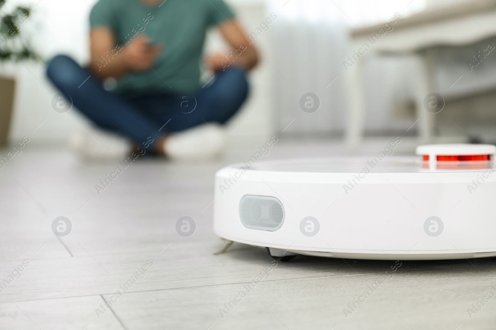 Photo of Man using robotic vacuum cleaner at home