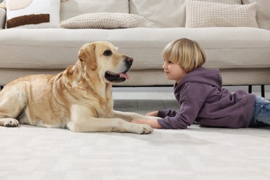 Photo of Cute little child with Golden Retriever on floor at home. Adorable pet