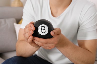 Photo of Man holding magic eight ball indoors, closeup