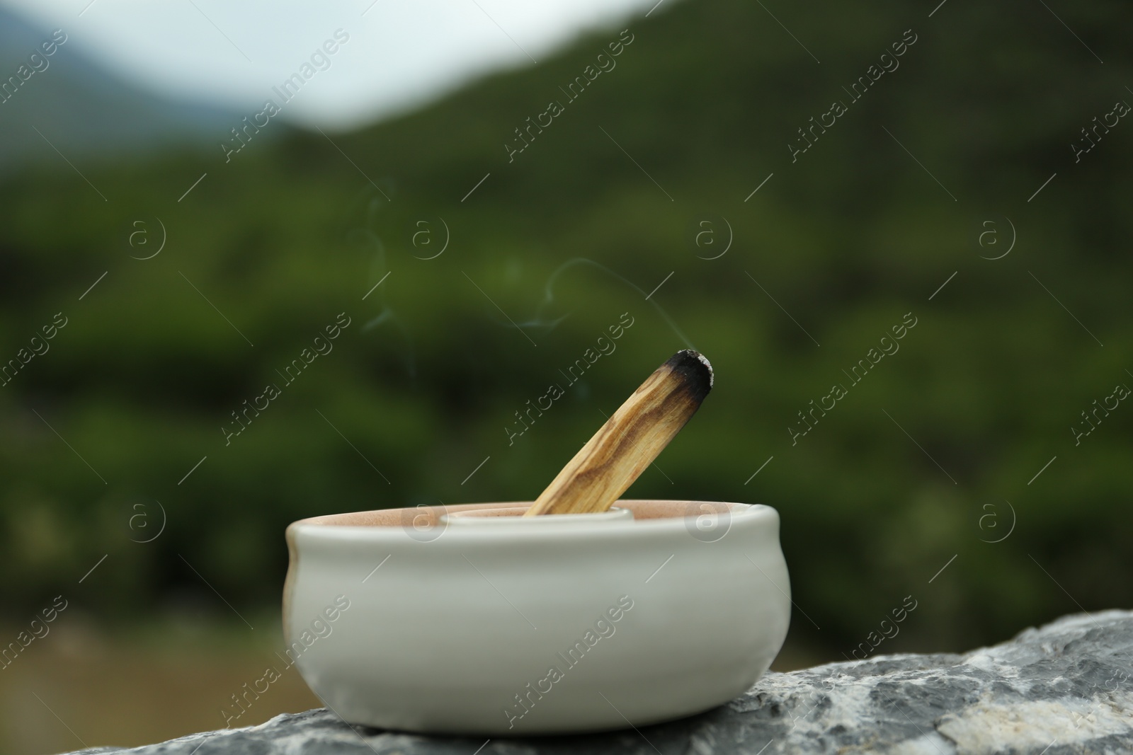 Photo of Burning palo santo stick on stone surface outdoors