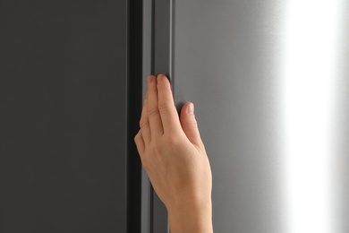 Woman opening refrigerator door, closeup. Space for text