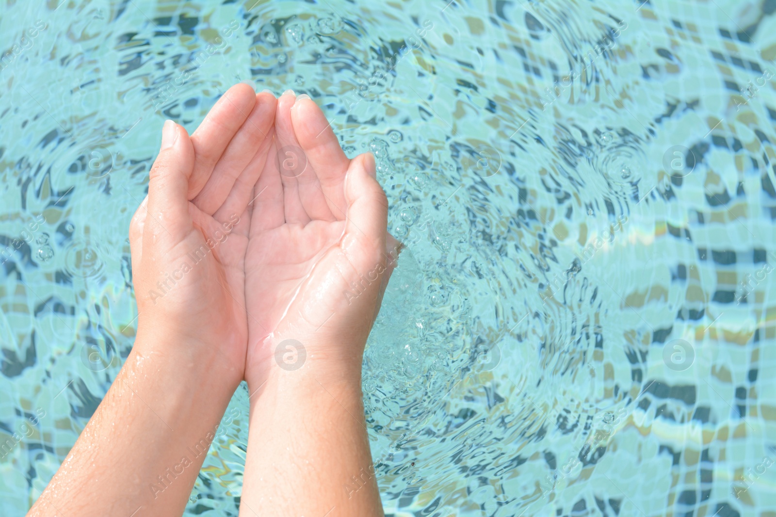 Photo of Girl holding water in hands above pool, closeup. Space for text