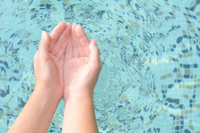 Girl holding water in hands above pool, closeup. Space for text