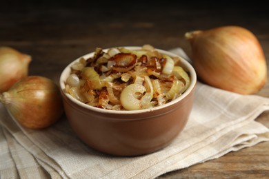 Tasty fried onion in bowl on wooden table