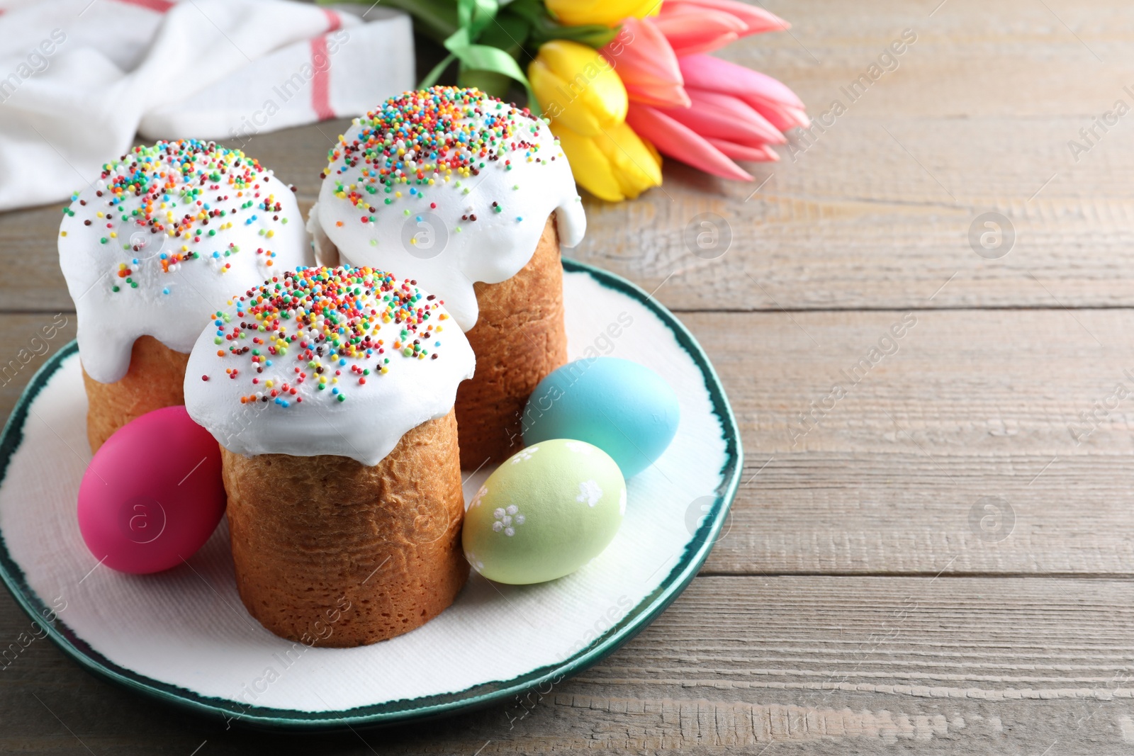 Photo of Beautiful Easter cakes and painted eggs on wooden table. Space for text