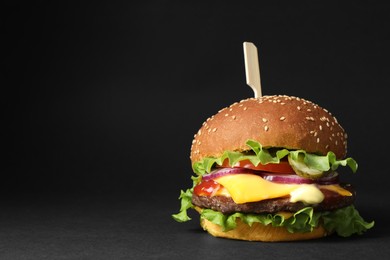 Photo of Delicious burger with beef patty and lettuce on black background, space for text