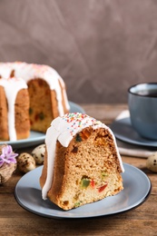 Piece of glazed Easter cake with sprinkles and candied fruits on wooden table