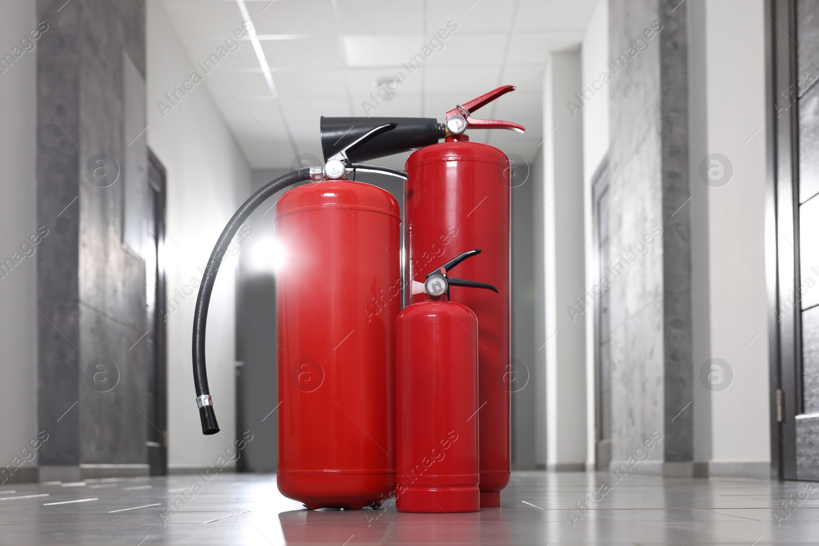 Photo of Three new red fire extinguishers in hall