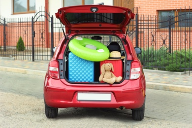 Suitcases, toys and hat in car trunk on city street