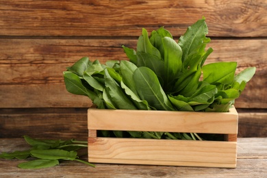Photo of Fresh green sorrel leaves in crate on wooden table