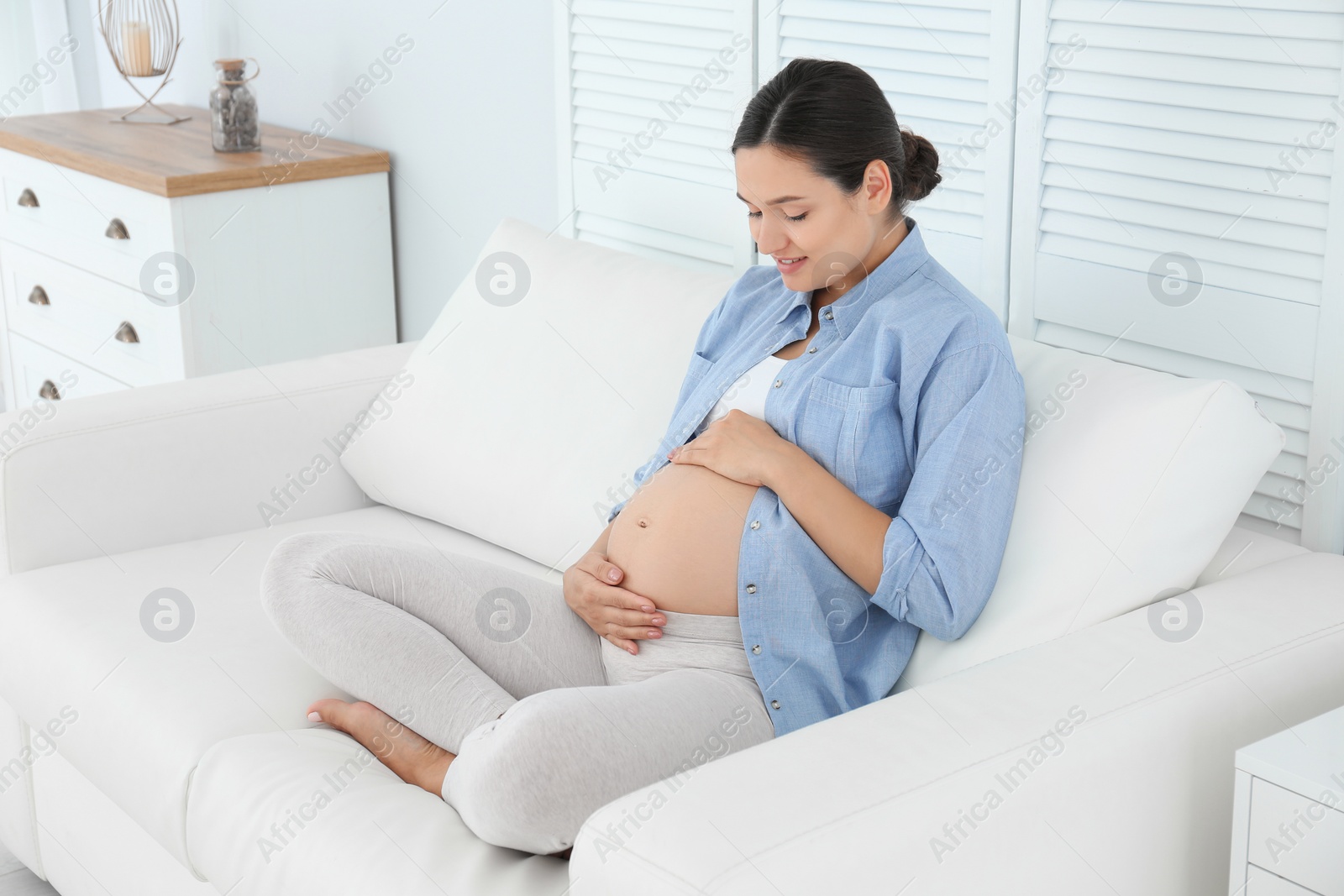 Photo of Beautiful pregnant woman sitting on sofa at home