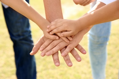 Photo of Parents and their children putting hands together outdoors, closeup. Family bonding