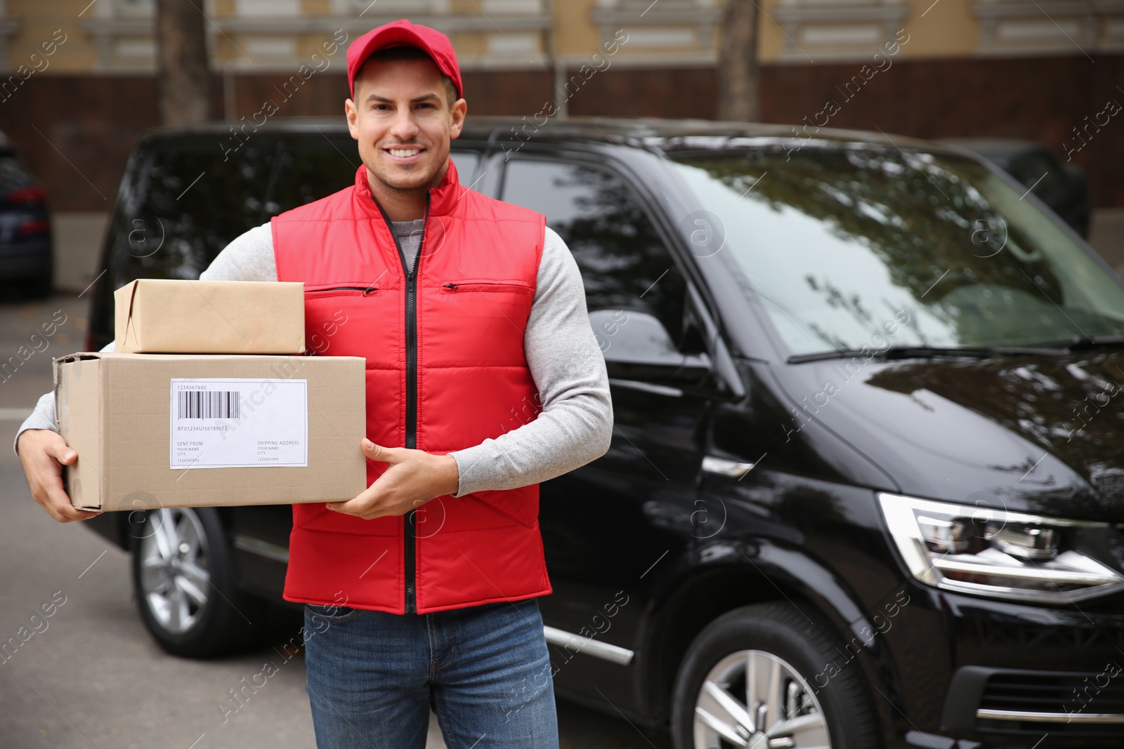 Photo of Courier with parcels near delivery van outdoors