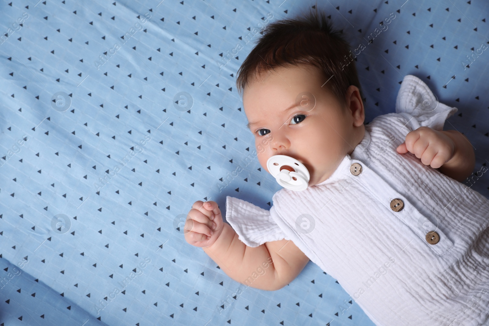 Photo of Cute little baby with pacifier lying on blanket, top view.  Space for text