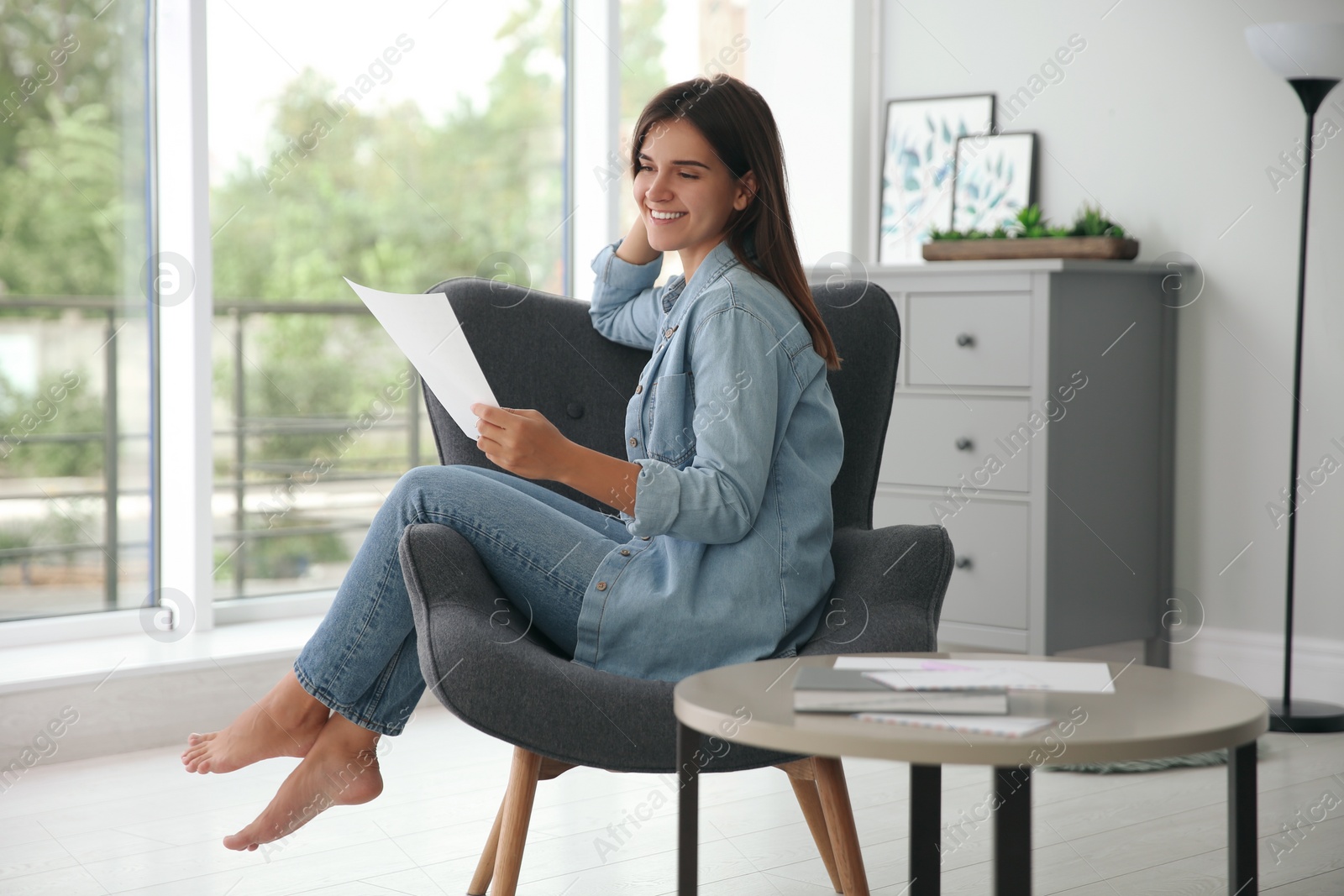 Photo of Young woman reading paper letter at home