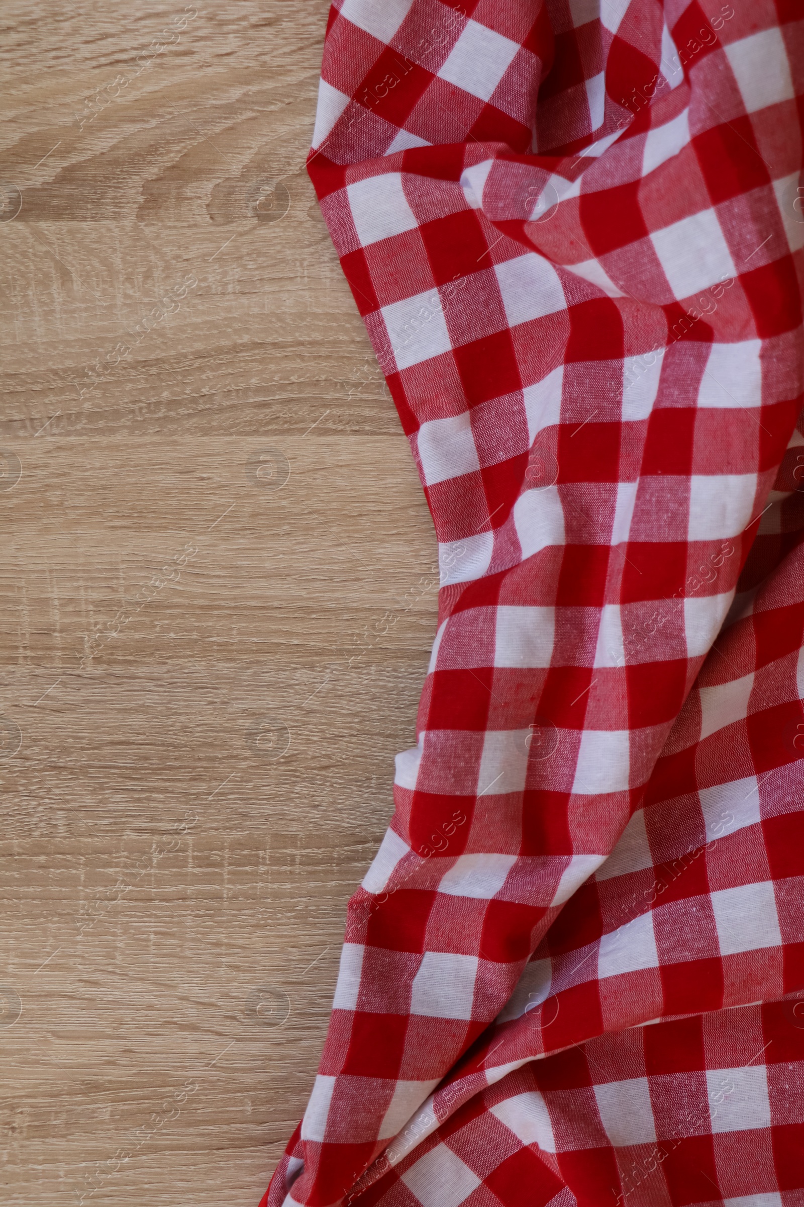 Photo of Checkered picnic cloth on wooden table, top view. Space for text