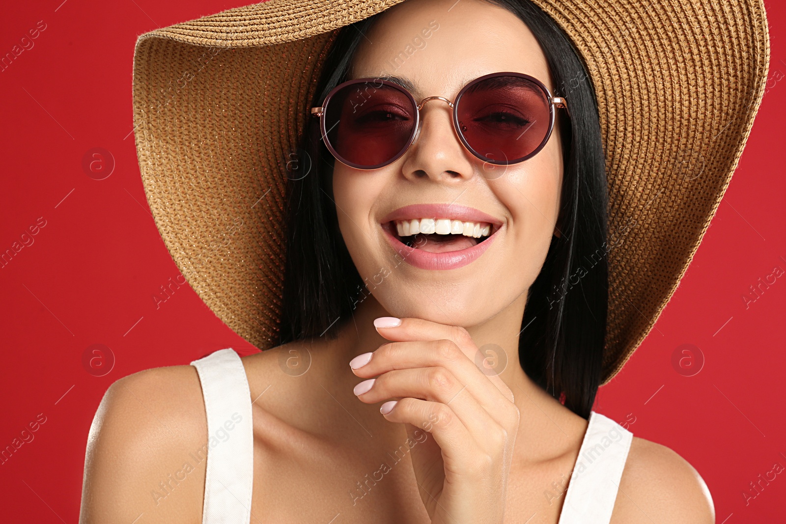 Photo of Beautiful woman wearing sunglasses on red background, closeup