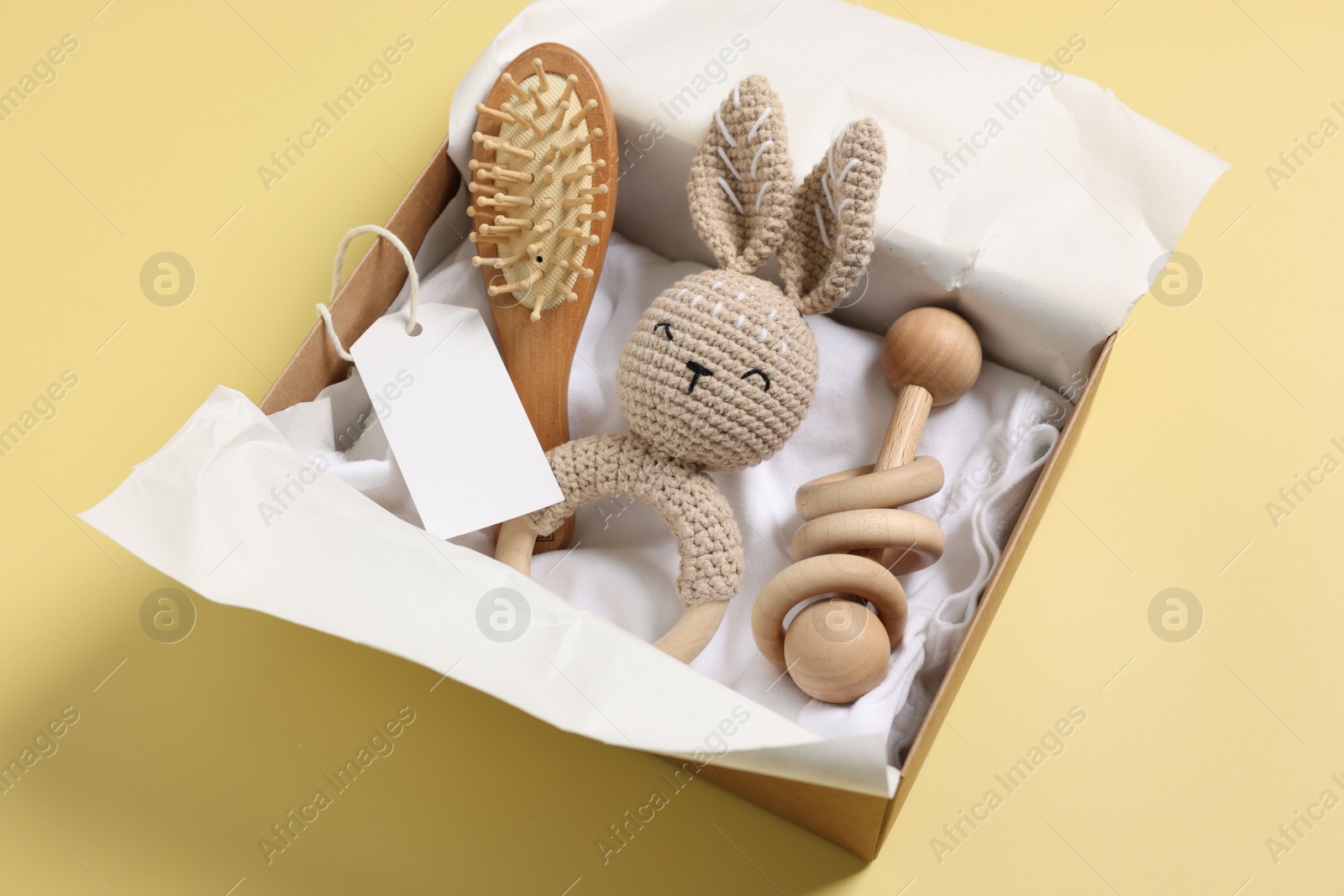 Photo of Different baby accessories and blank card in box on yellow background