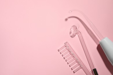 Photo of Modern darsonval and different nozzles on pink background, flat lay. Space for text