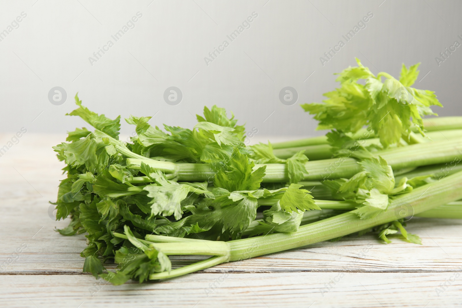 Photo of Fresh ripe green celery on white wooden table, closeup