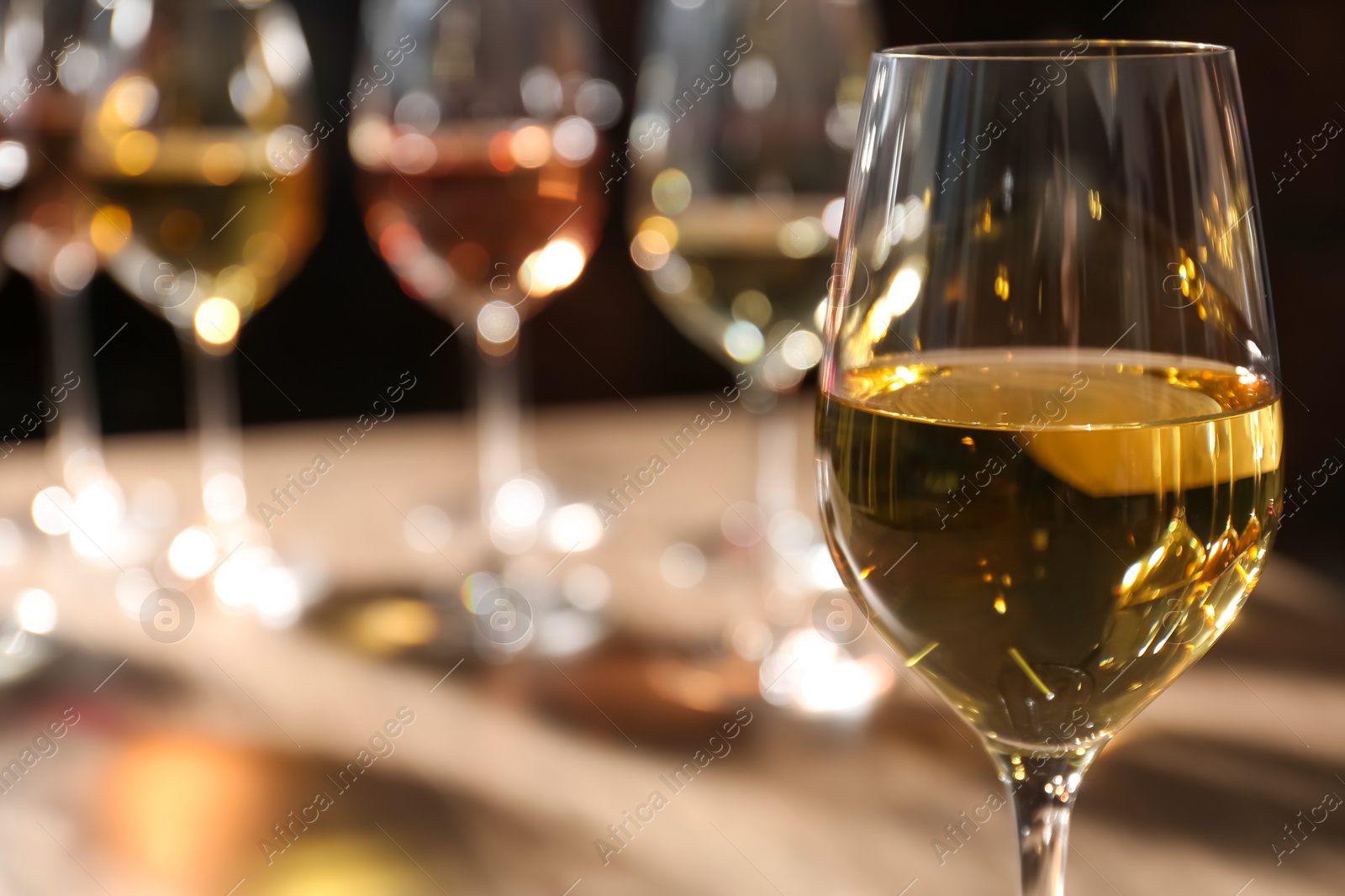 Photo of Tasty white wine in glass against blurred background, space for text