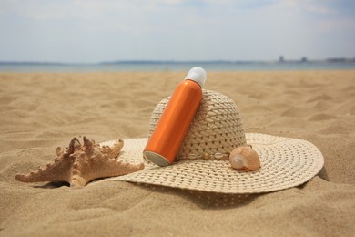 Sunscreen, hat and starfish on sand. Sun protection care