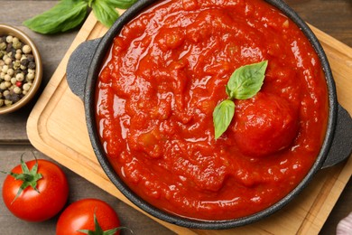 Photo of Homemade tomato sauce in bowl and ingredients on wooden table, flat lay