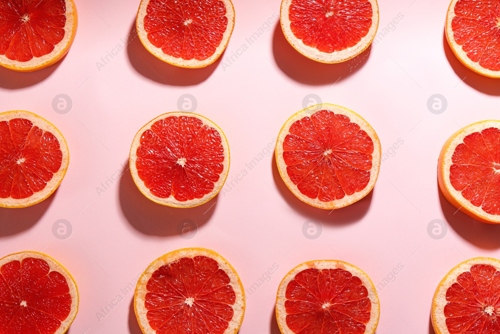 Photo of Tasty ripe grapefruit slices on pink background, flat lay